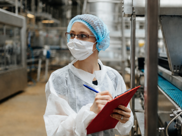 Profissional em ambiente industrial realizando inspeção de linha produtiva, ilustrando interdições Anvisa e controle de qualidade industrial.