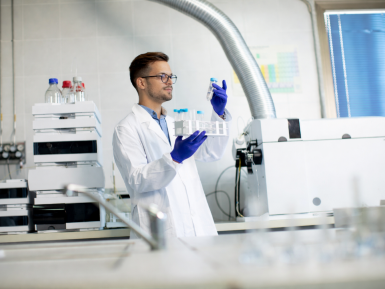 Cientista em laboratório analítico avaliando vial de amostra diante de sistemas HPLC e UHPLC, ambiente moderno de cromatografia representando pesquisa, desenvolvimento e indústria analítica.