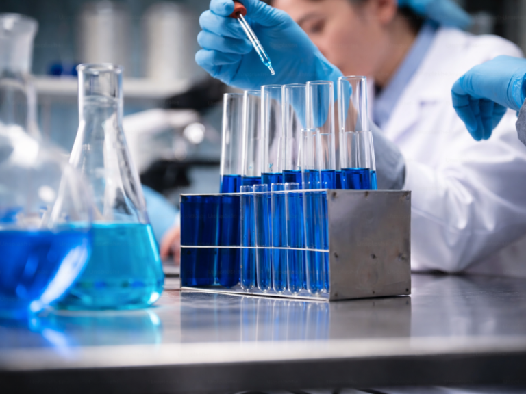 Mãos com luvas manipulando tubos de ensaio em laboratório clínico, representando o controle da qualidade da água na bioquímica clínica para garantir precisão dos resultados analíticos.