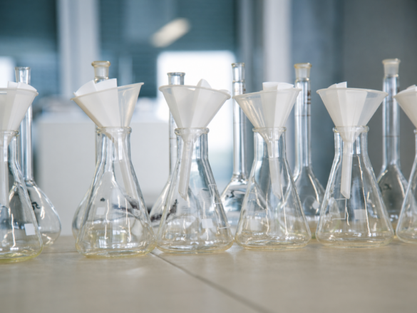 Laboratório analítico moderno com preparação de amostras avançada, mostrando frascos Erlenmeyer com funis e filtros em bancada limpa, ambiente controlado e iluminação fria, representando técnicas de microextração e uso de sorbentes seletivos para análises de alta precisão.